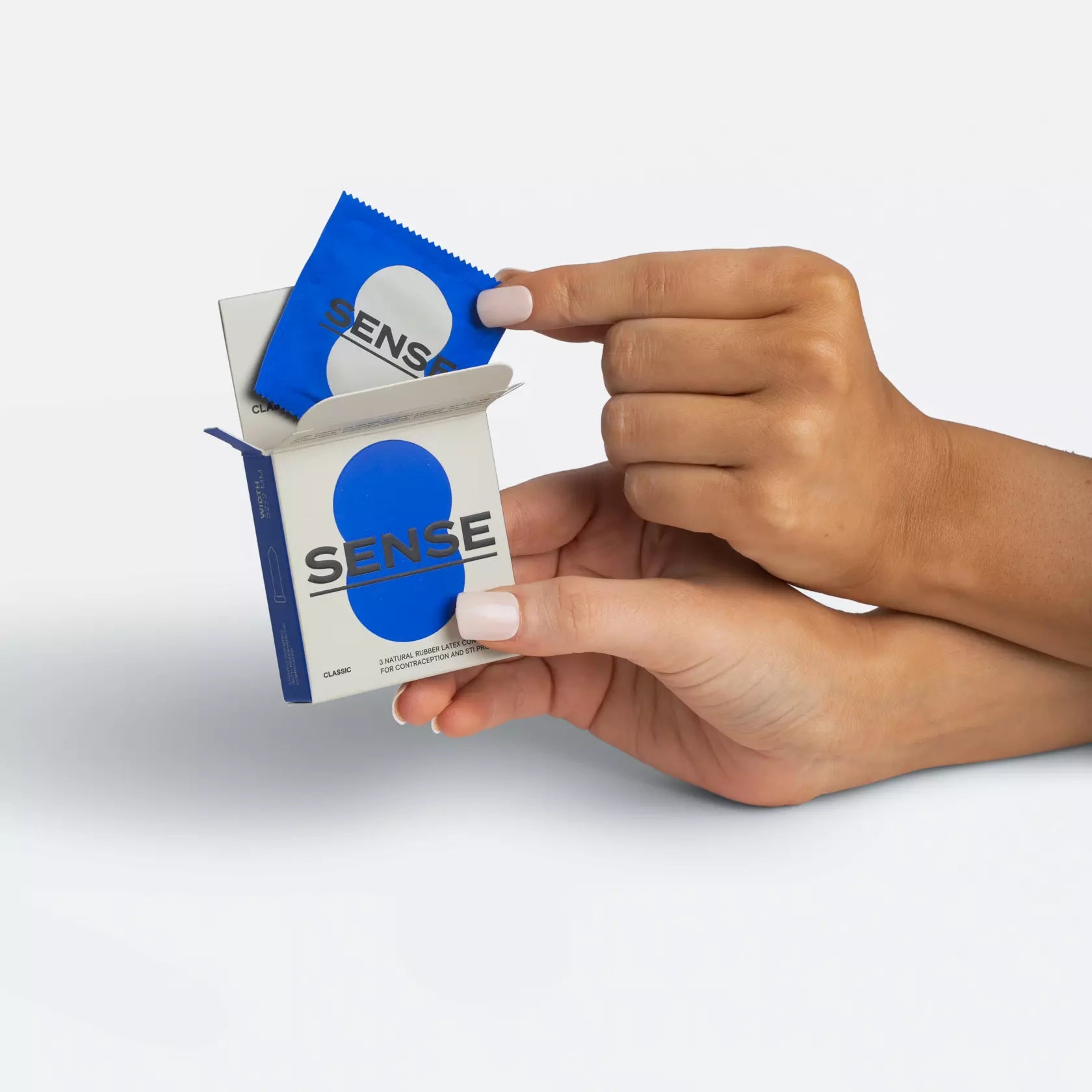 Woman hands opening a 3 pack of Sense premium natural rubber latex condoms 